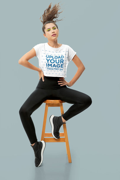 Crop Top Mockup Featuring a Woman With an Athleisure Look Sitting on a Stool