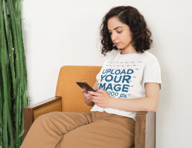 T-Shirt Mockup of a Serious Woman With Curly Hair Checking Her Phone