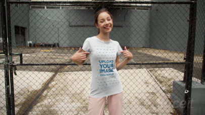 Video of a Woman Pointing at Her T-Shirt by a Fence