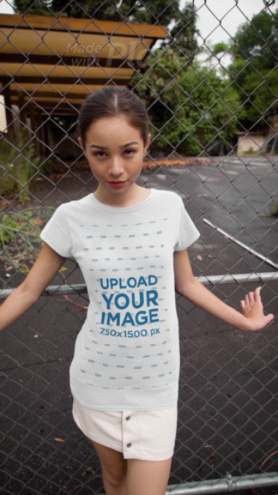 Video of a Woman Wearing a T-Shirt and Leaning Against a Metal Fence 