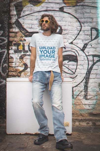 90s-Styled T-Shirt Mockup Featuring a Man Posing Against a Graffitied Wall m12537