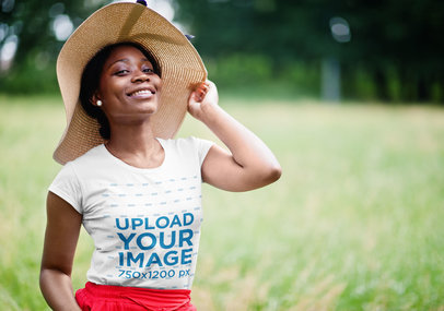 T-Shirt Mockup of a Happy Woman Posing with a Hat on an Open Field