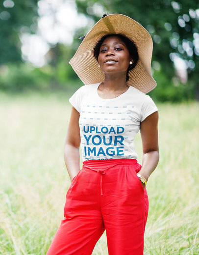 T-Shirt Mockup Featuring a Woman Posing at a Green Grass in the Park