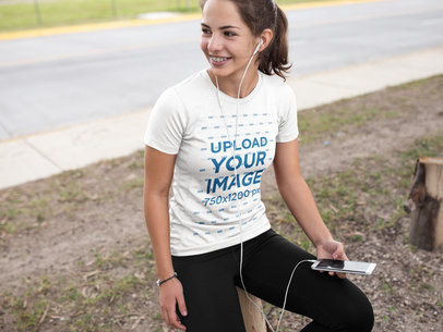 Fitness Mockup of a Woman Wearing Custom Sportswear While Listening to Music Outdoors