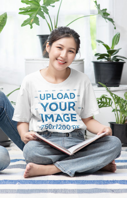T-Shirt Mockup of a Smiling Woman Sitting on the Floor With an Open Book