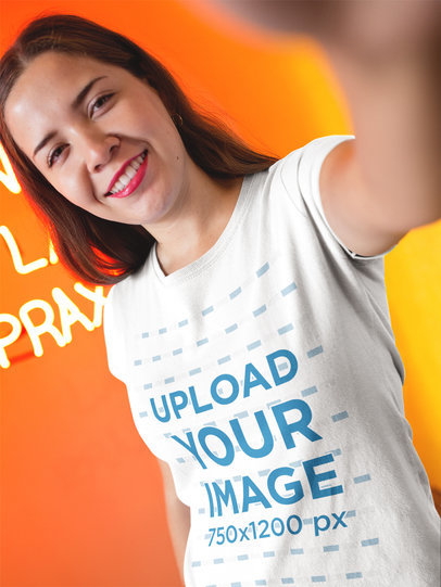 Selfie Mockup of a Woman Wearing a T-Shirt Inside an Orange Room