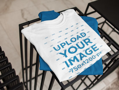 Mockup of a Folded Pair of T-Shirts on Top of Furniture Indoors a16945
