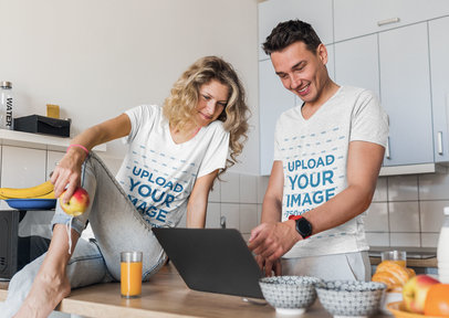 V-Neck T-Shirt Mockup Featuring a Couple Using a Laptop in Their Kitchen