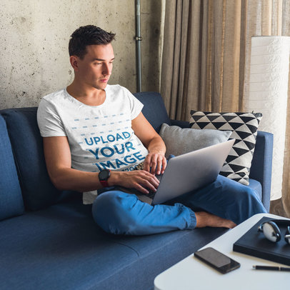 Heather Tee Mockup Featuring a Man on a Coach Using His Laptop