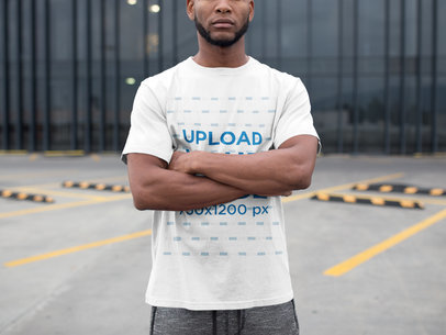 Man with Crossed Arms Wearing a T-Shirt Mockup at a Parking Lot