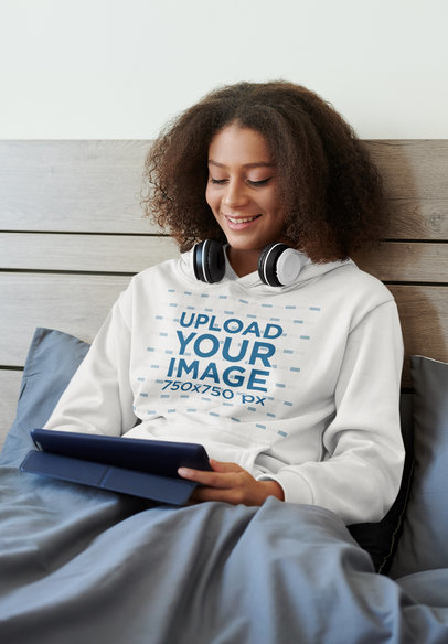 Hoodie Mockup of a Young Woman Enjoying Some Music in Bed