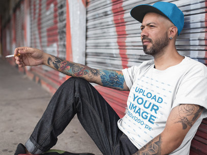 Man Smoking While Wearing a Round Neck T-Shirt Mockup Against a Closed Metal Curtain