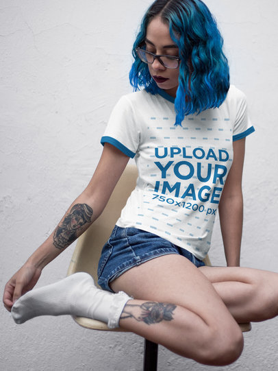 Mockup of a Tattooed Woman Wearing a Ringer T-Shirt While Sitting Without Shoes