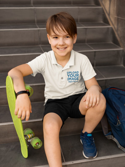 Polo Shirt Mockup of a Smiling Kid with a Penny Board Sitting on a Staircase