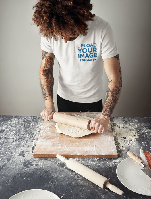 Polo Shirt Mockup Featuring a Tattooed Man Flattening Dough With a Rolling Pin