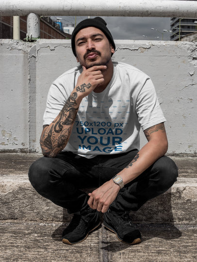 Chilling Tattooed Man Wearing a Round Neck Tee Mockup While Squatting on a Bridge a17075
