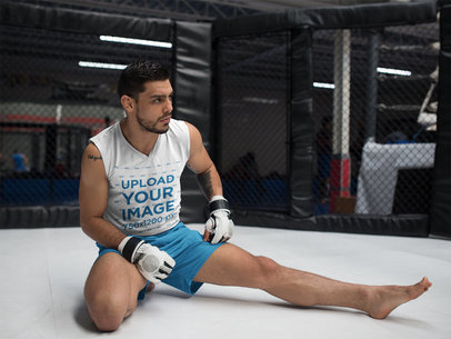 Sleeveless Shirt Mockup of a Man Stretching his Legs While Wearing Inside an MMA Cage