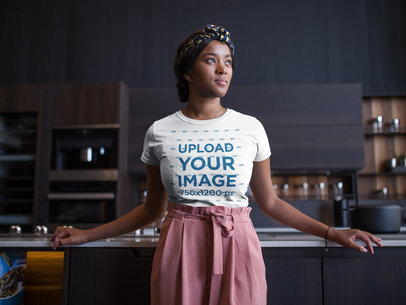 Mockup of a Woman Wearing a Round Neck T-Shirt While Leaning against a Kitchen Counter