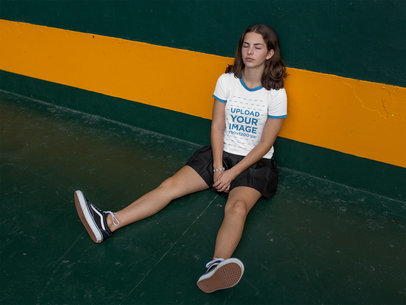 Woman Resting While Sitting Against a Wall Wearing a Ringer T-Shirt Mockup