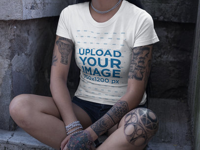 Cropped Face Woman Wearing a Round Neck Tee Mockup while Sitting at a Concrete Spot