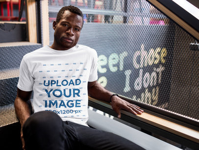 Mockup of a Guy Wearing a Round Neck Tee Template While Sitting on Stairs
