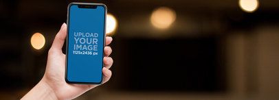 Mockup of an iPhone 11 Pro Being Held Against a Blurry Background