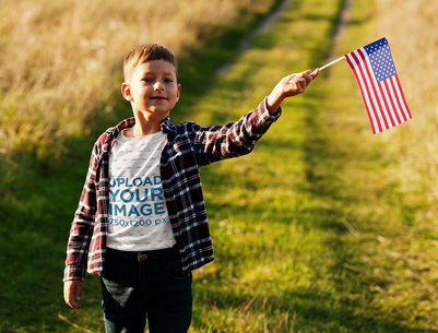 T-Shirt Mockup of a Patriotic Little Boy Holding a USA Flag
