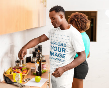 T-Shirt Mockup of a Man Cooking a Meal at Home with His Girlfriend 