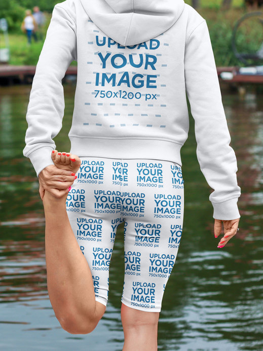 Hoodie and Bike Shorts Mockup of a Woman Stretching by a Pond