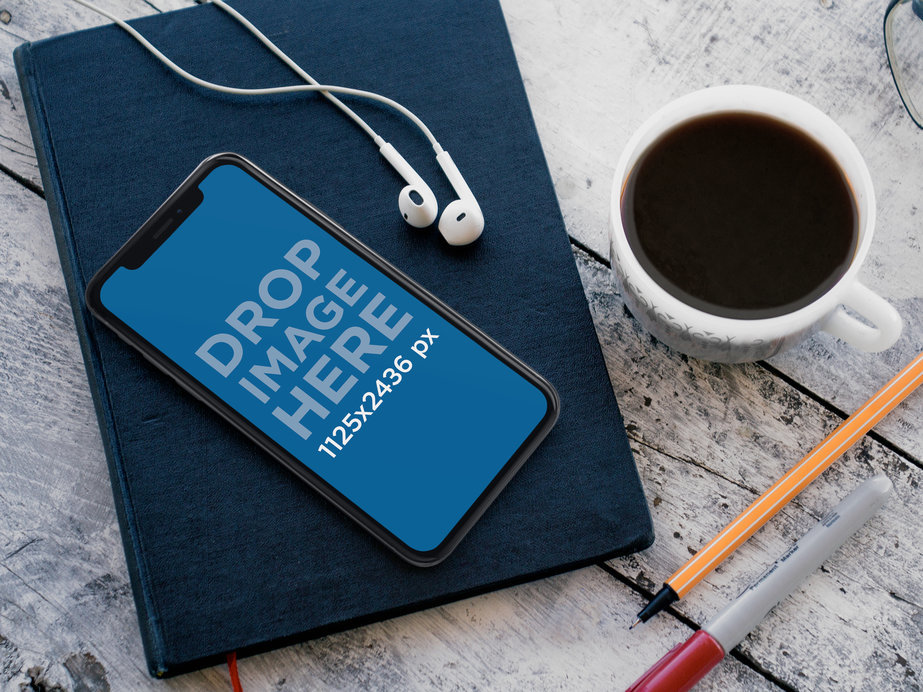 iPhone 11 Pro Mockup Lying on top of a Book While Near a Coffee Cup and Headphones