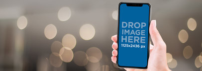 Mockup of an iPhone 11 Pro Being Held Against a Blurry Background
