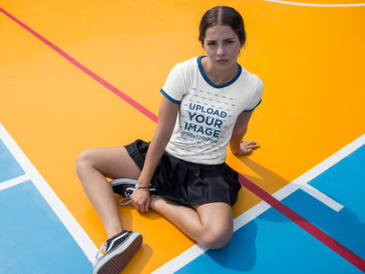 Woman Wearing a Ringer Tee Mockup While Sitting on a Basketball Court