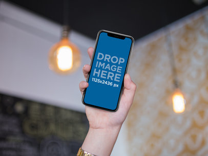 iPhone X Mockup Being Held by a Girl Inside a Room with Lightbulbs a17310