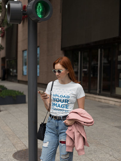 Woman Wearing a Tshirt Mockup While Using her Phone Crossing the Street