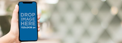 Woman Holding an iPhone 11 Pro Mockup Against a Blurred Background with Triangles