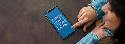 Mockup of a Young Woman using an iPhone 11 Pro on a Wooden Table