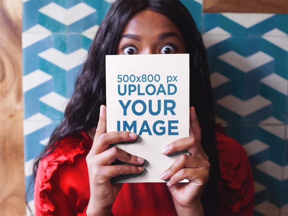 Surprised Woman Holding a Book Mockup While Against a Tiles Wall