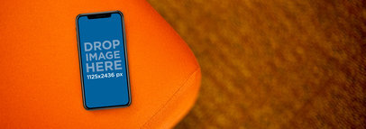 iPhone X Mockup Lying on the Corner of an Orange Sofa a17377