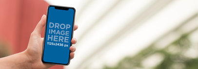 iPhone 11 Pro Mockup Being Held Inside a Red and White Building
