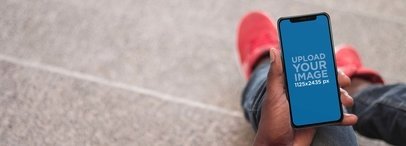 Man Holding an iPhone 11 Pro Mockup While Sitting on a Stone Staircase