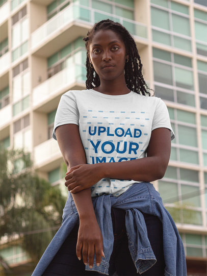 Mockup of a Womanl Wearing a Round Neck Tee Template While Standing Near a Tall Building 17322