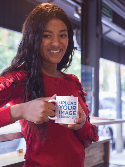 Woman Holding a Coffee Mug Mockup While at a Coffee Store 