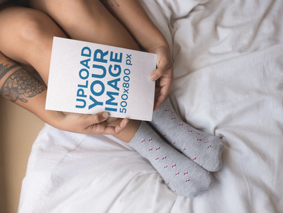 Woman Holding a Book Mockup Near her Feet While in Bed a17305