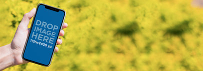 Mockup of an iPhone 11 Pro Being Held While in a Flowers Garden