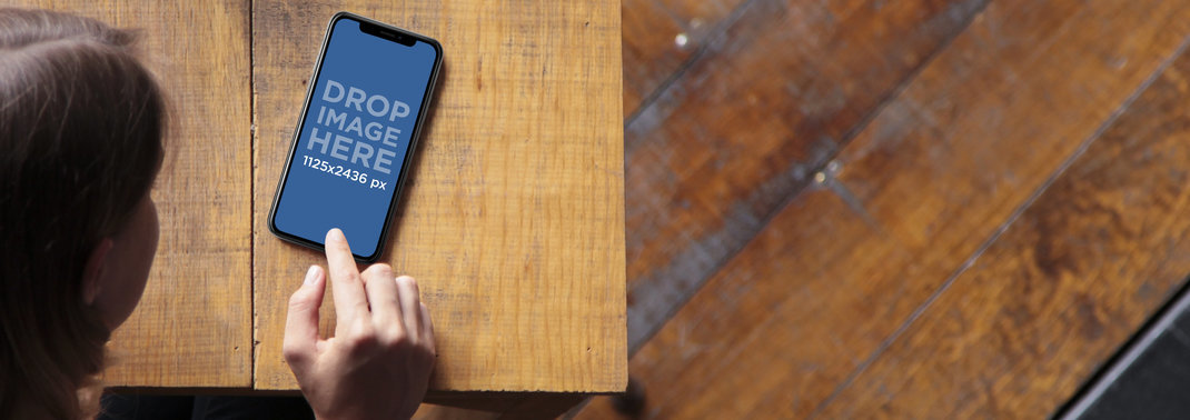 Mockup of an iPhone 11 Pro Being Used by a Woman on the Table