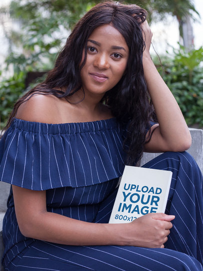 Portrait of a Beautiful Woman Holding a Book Mockup While at a Park