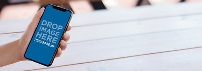 iPhone 11 Pro Mockup Held by a Woman Waiting at a Table