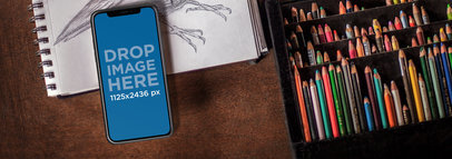 iPhone X Mockup Lying on Top of a Drawing Sketchbook a17389