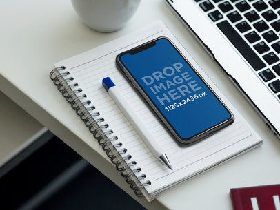 Mockup of an iPhone X Lying on an Office Desk a17390