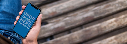 Man Holding an iPhone 11 Pro Mockup While Sitting on a Wooden Bench